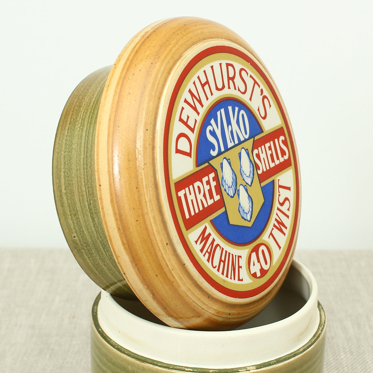 Advertising & Haberdashery Interest - a novelty ceramic jar, in the form of a faux oversized cotton reel, press close cover with printed design, 'DEWHURST'S SYLKO THREE SHELLS, MACHINE TWIST 40', finished in green, 15.5cm high