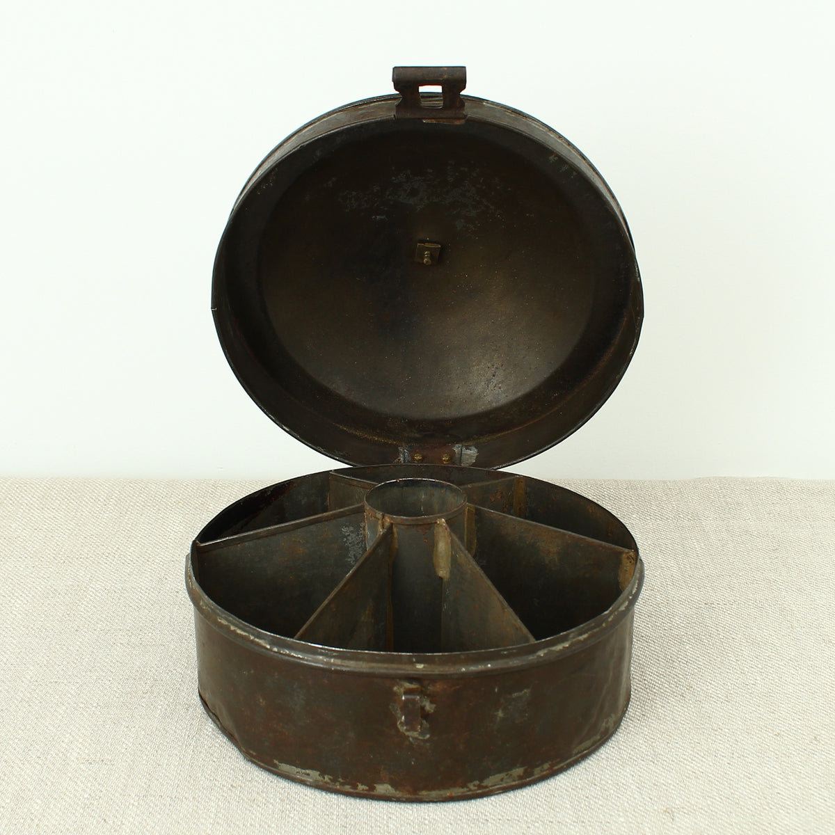 A 19th century metal circular spice tin, the fitted interior with sectional divides, domed lid with brass ring handle, metal clasp, 11cm high, 17cm diameter