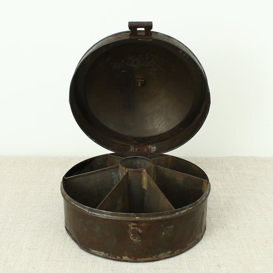 A 19th century metal circular spice tin, the fitted interior with sectional divides, domed lid with brass ring handle, metal clasp, 11cm high, 17cm diameter