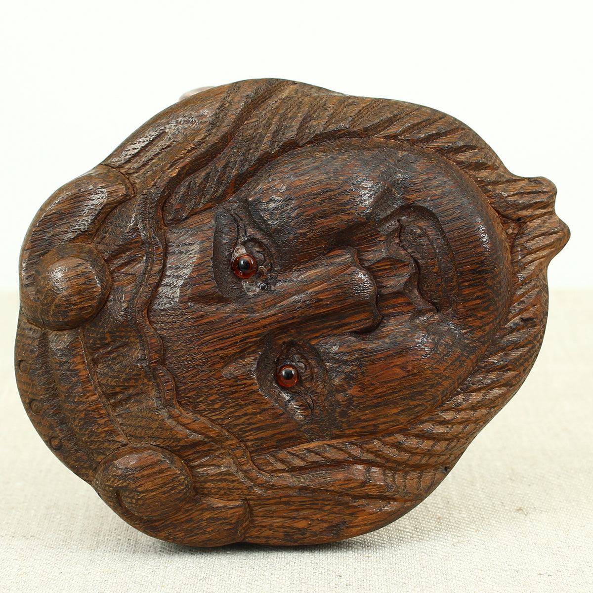 Treen - a carved oak fragment or furniture embellishment, carved as a mask with glass eyes