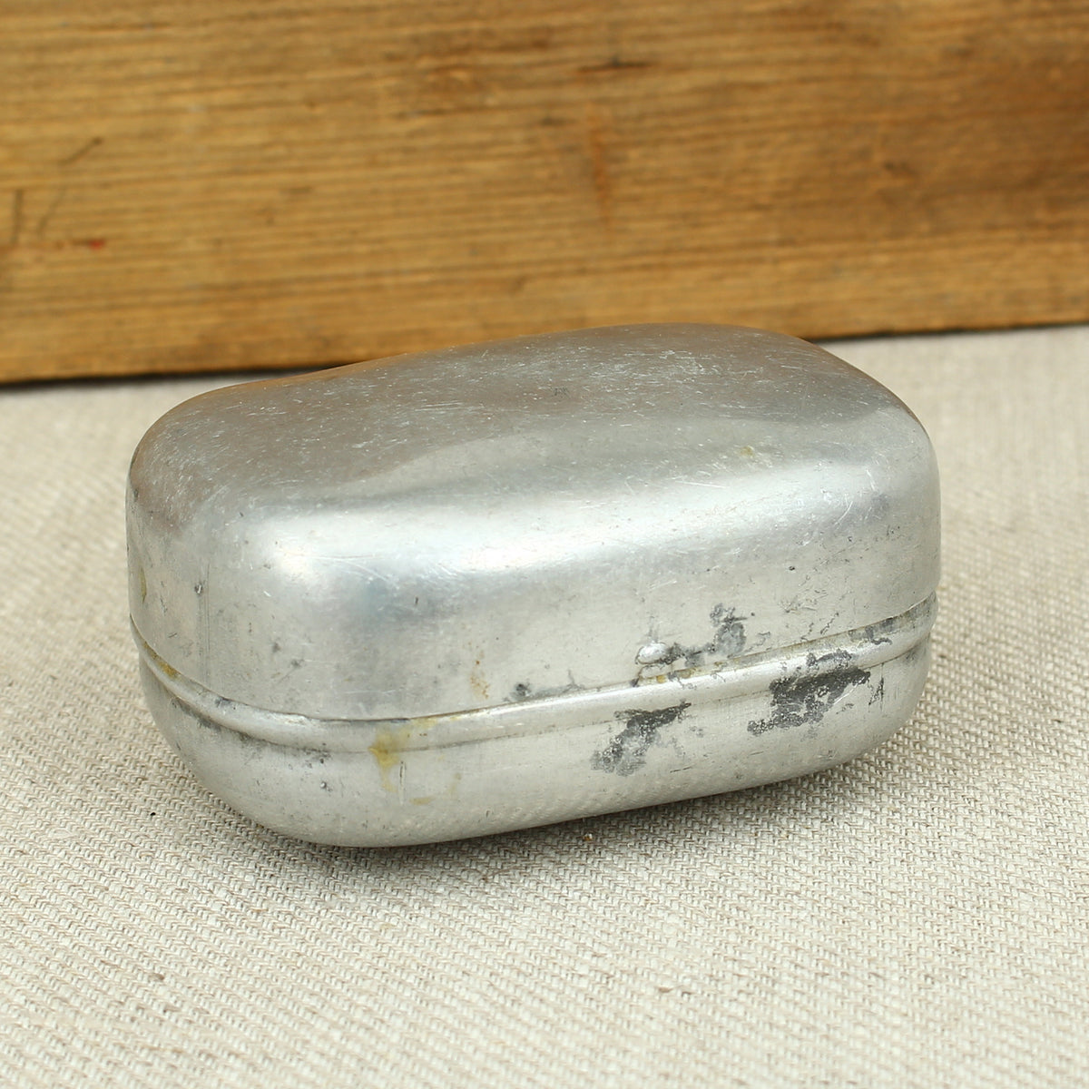 A World War II British Army aluminium soap tin, impressed marks 'W.S.L., 1945, (Broad Arrow), CC 1114'