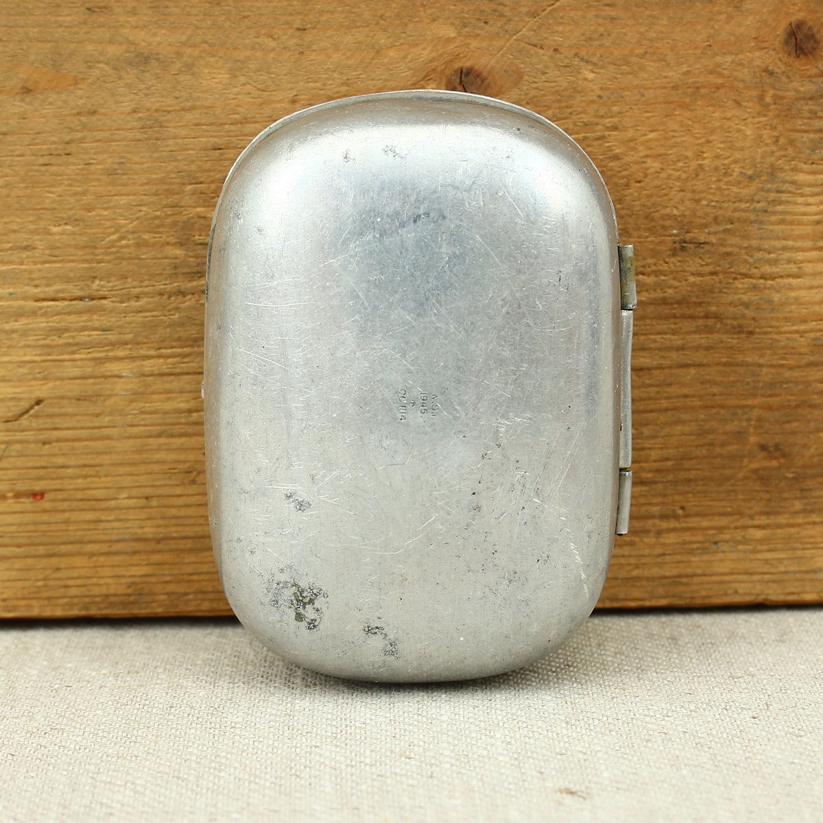 A World War II British Army aluminium soap tin, impressed marks 'W.S.L., 1945, (Broad Arrow), CC 1114'