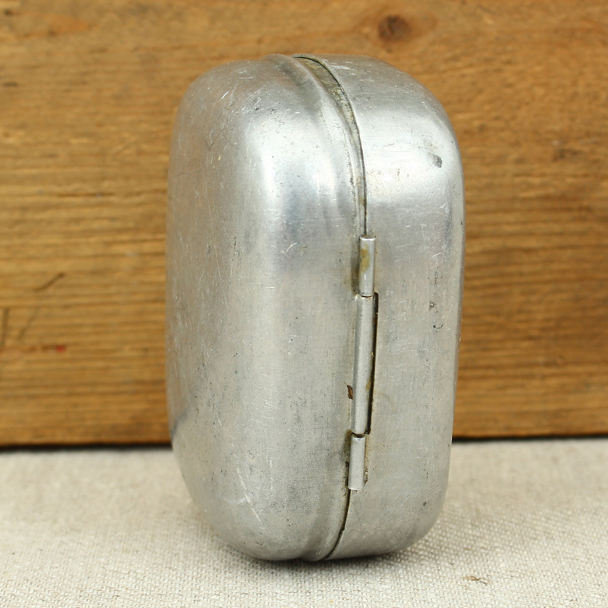 A World War II British Army aluminium soap tin, impressed marks 'W.S.L., 1945, (Broad Arrow), CC 1114'