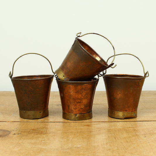 A collection of four early 20th century copper and brass miniature buckets