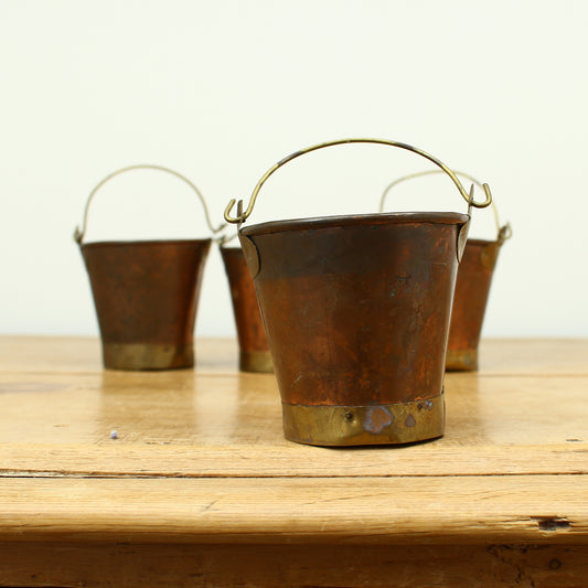 A collection of four early 20th century copper and brass miniature buckets
