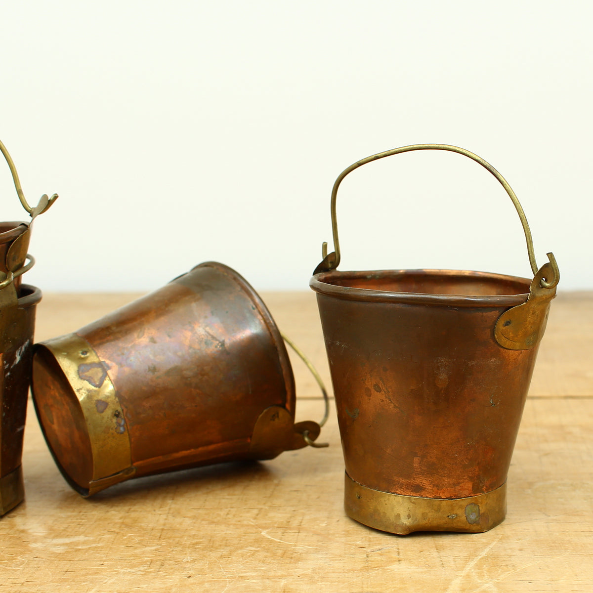 A collection of four early 20th century copper and brass miniature buckets