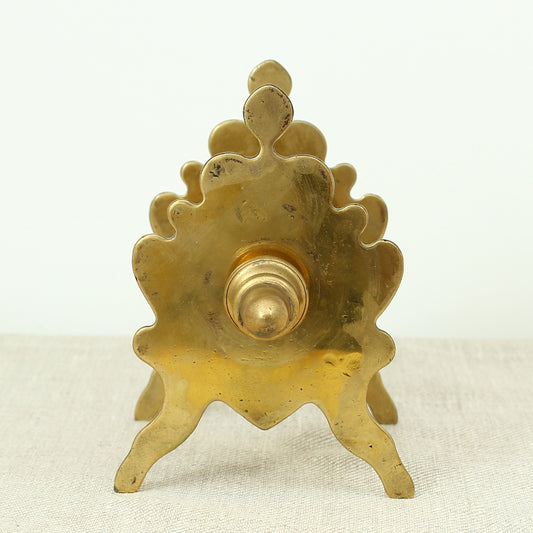 A late 19th century or early 20th century brass money box/bank, cylindrical central section with single money slot, shaped end pieces forming a combination pen rest, threaded finials to each end, 13.5cm high, 20cm wide