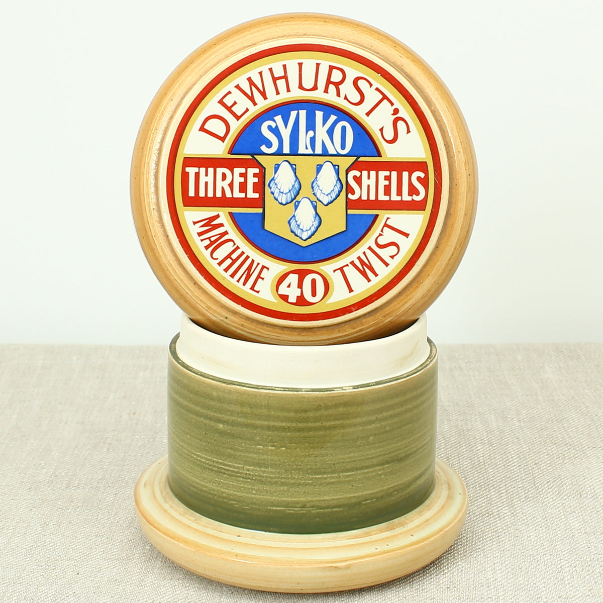 Advertising & Haberdashery Interest - a novelty ceramic jar, in the form of a faux oversized cotton reel, press close cover with printed design, 'DEWHURST'S SYLKO THREE SHELLS, MACHINE TWIST 40', finished in green, 15.5cm high