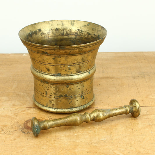 A 19th century bronze mortar and pestle, cylindrical form with girdle and everted rim