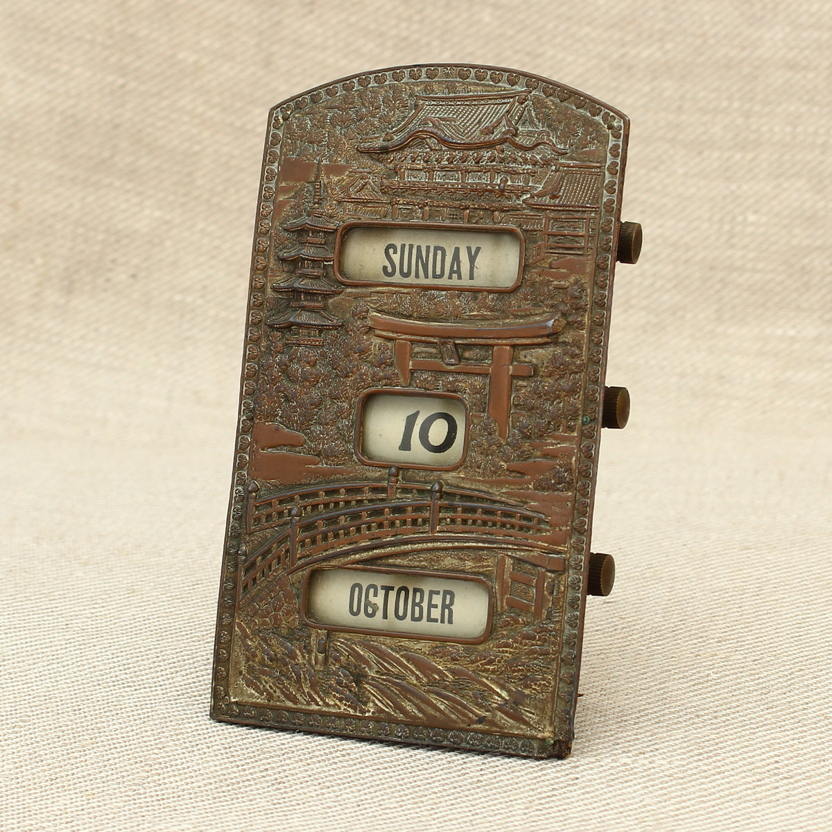 An early 20th century Japanese perpetual desk calendar, the cast metal face plate probably manufactured from antimony or a similar alloy