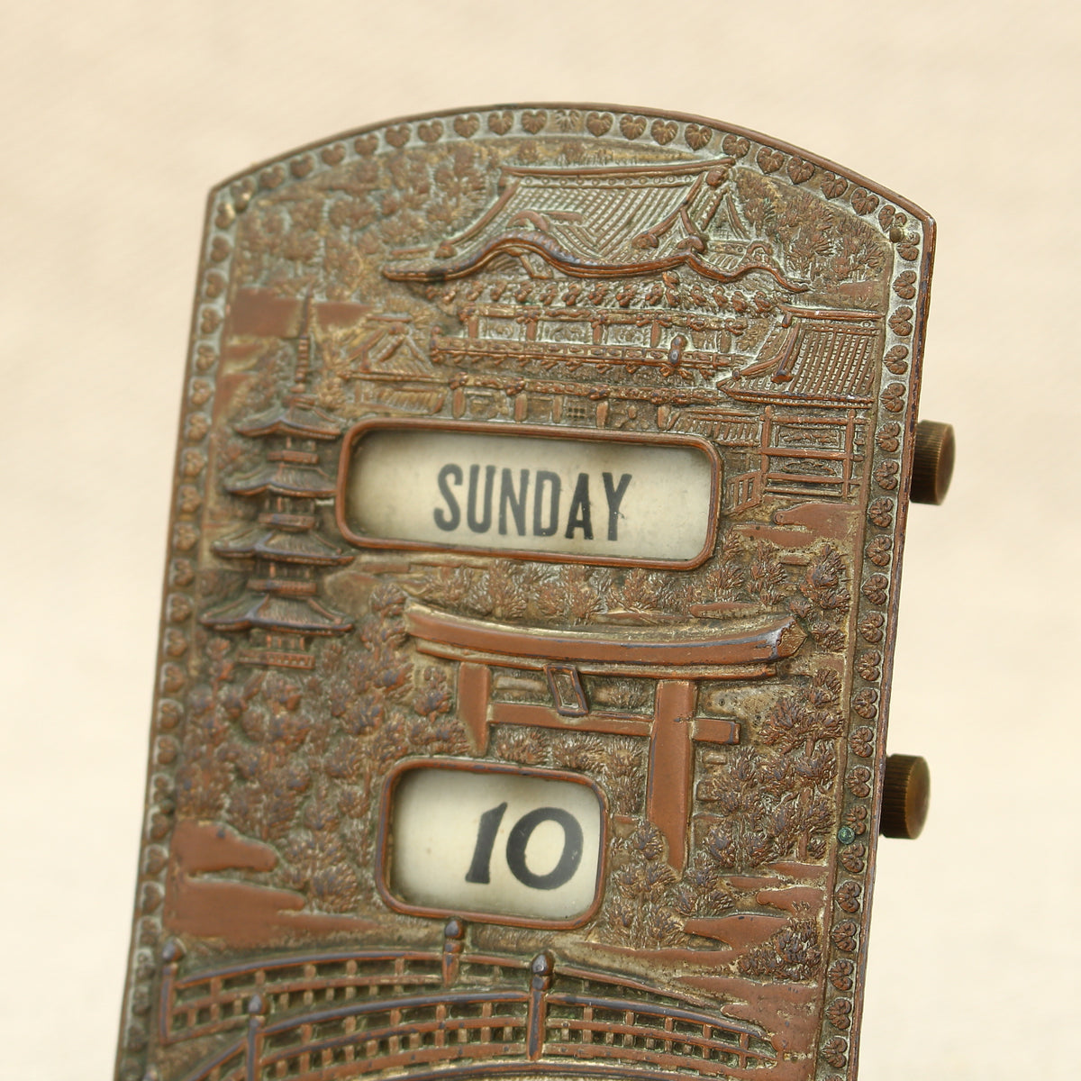 An early 20th century Japanese perpetual desk calendar, the cast metal face plate probably manufactured from antimony or a similar alloy