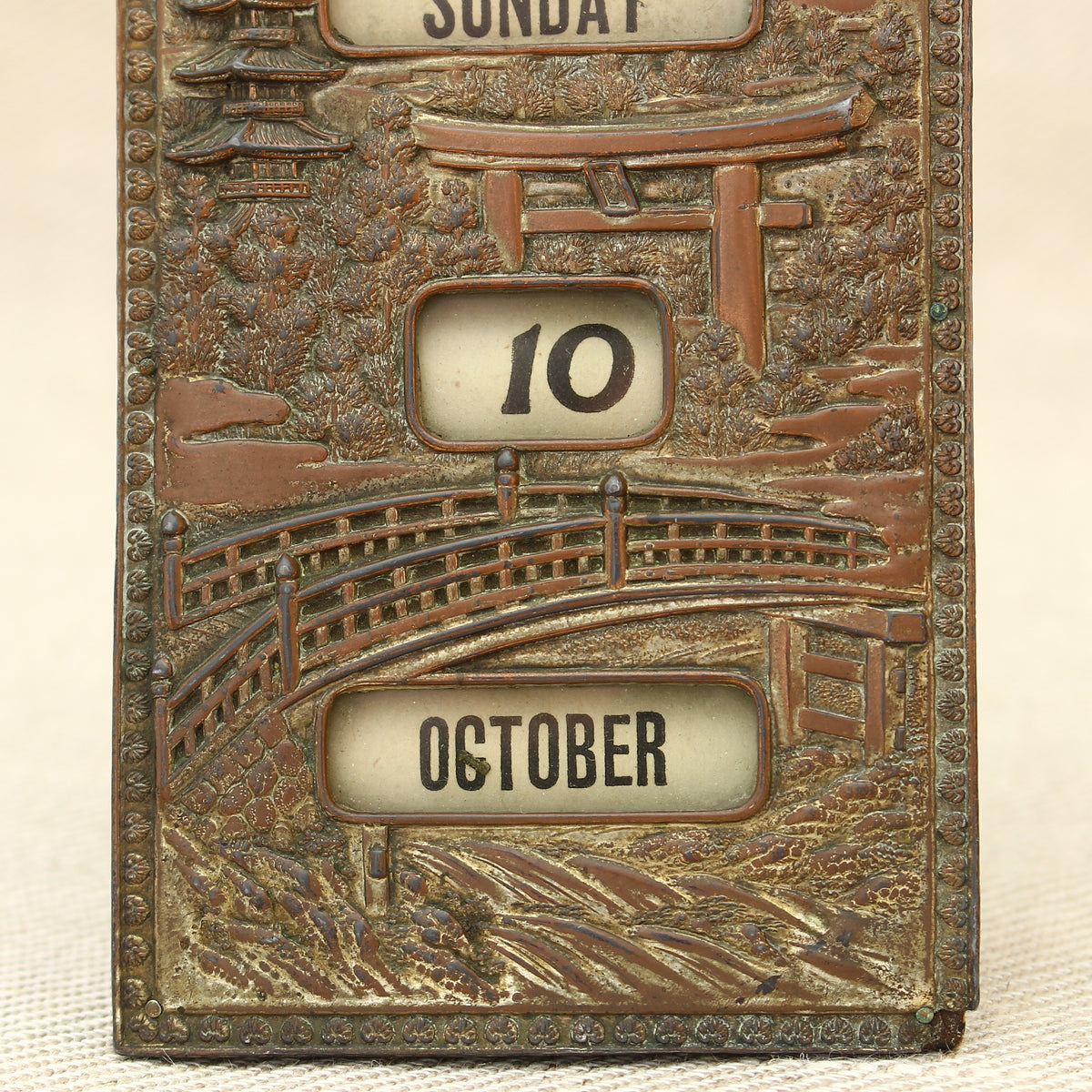 An early 20th century Japanese perpetual desk calendar, the cast metal face plate probably manufactured from antimony or a similar alloy