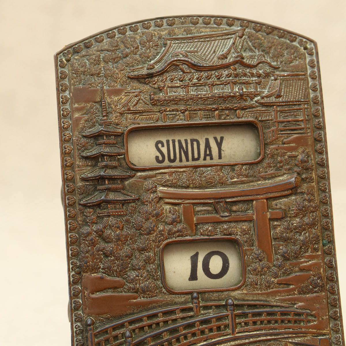 An early 20th century Japanese perpetual desk calendar, the cast metal face plate probably manufactured from antimony or a similar alloy
